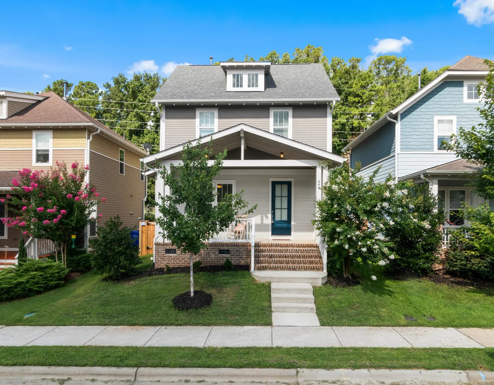 A craftsman-style family home with a front porch on a tree-lined Fox River town street